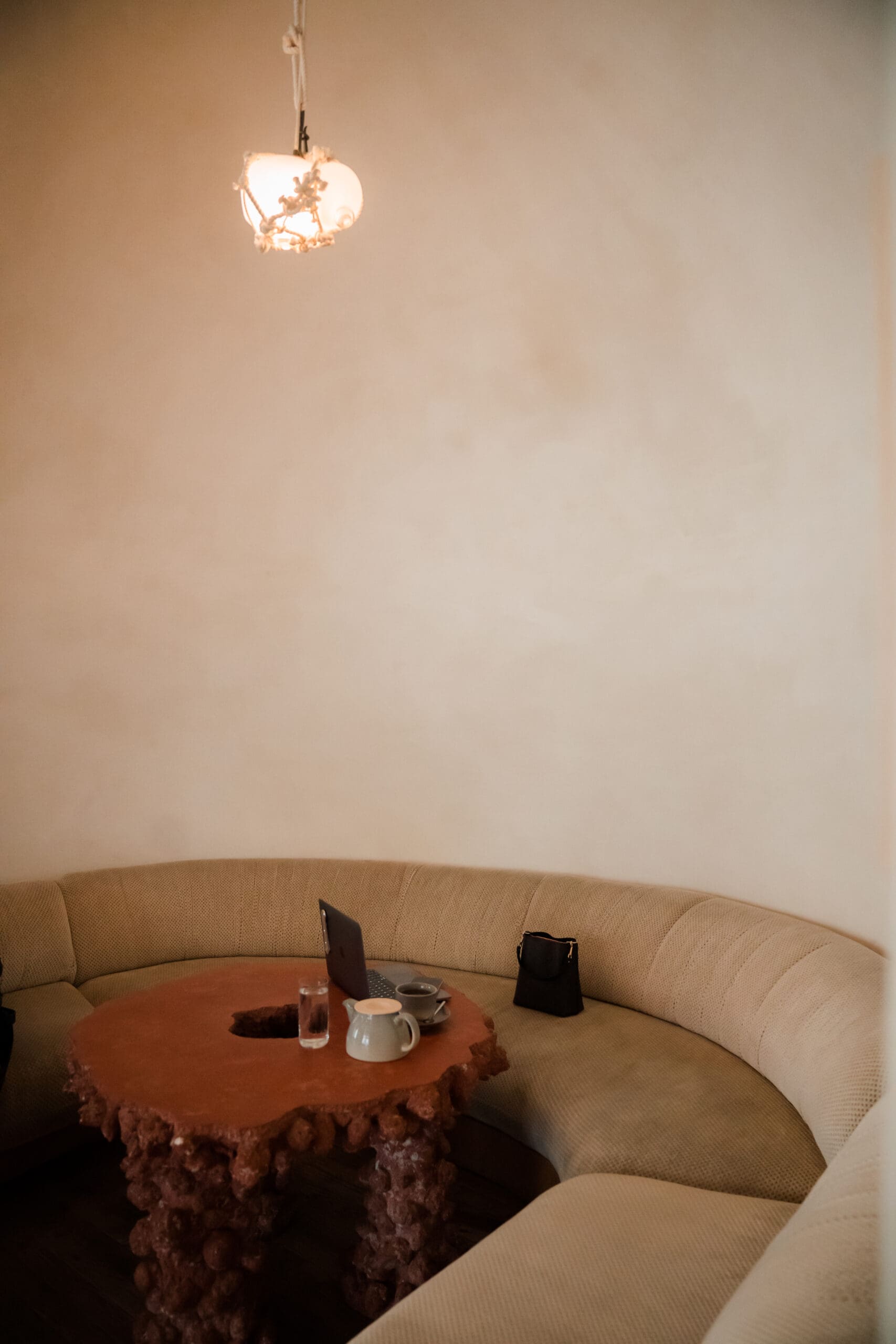 Warm, stylish workspace featuring a curved beige sofa, a sculptural coffee table, and a laptop setup under soft lighting — perfect for creative focus and blog writing.