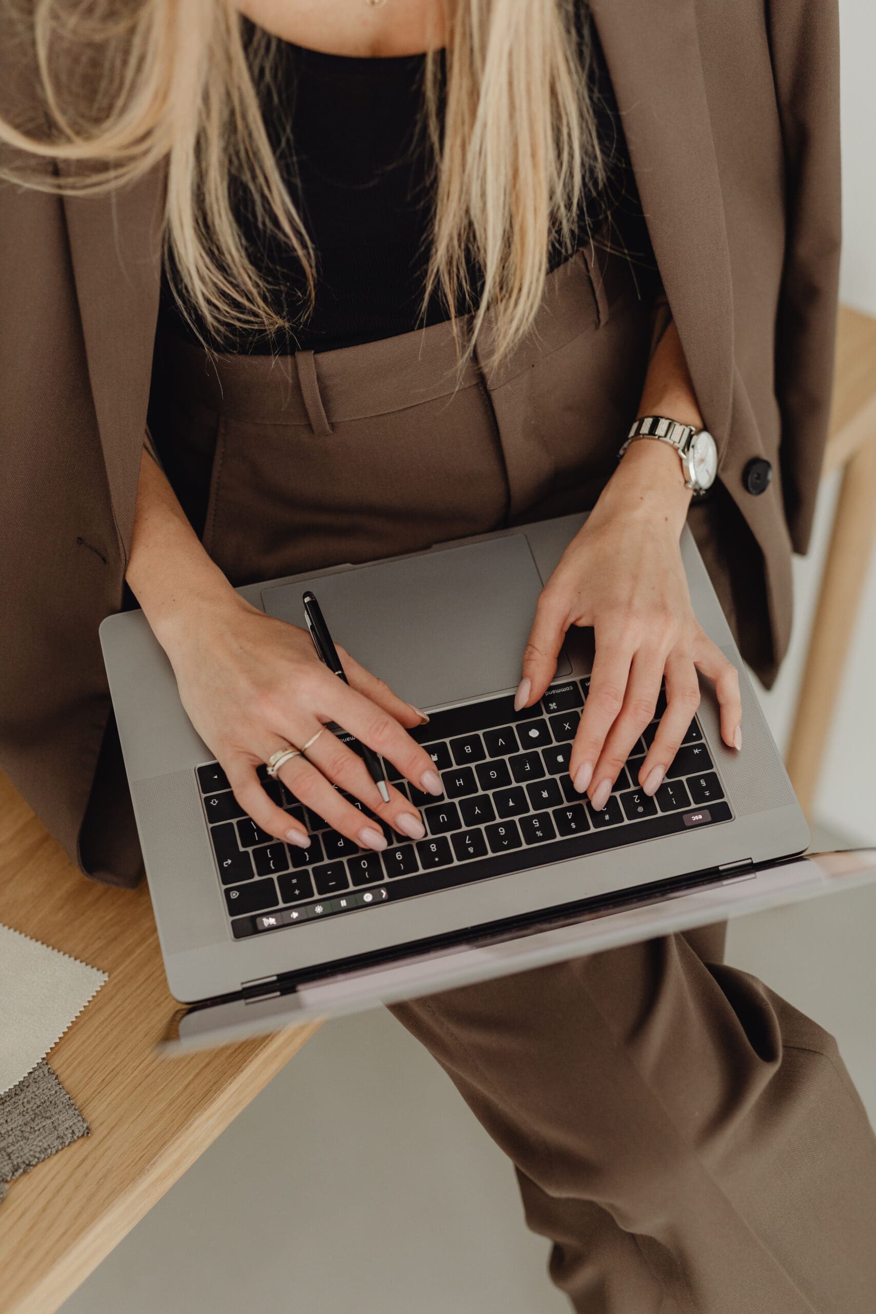 Shopify web design expert wearing a brown suit, working on a laptop at a wooden desk — representing modern, professional e-commerce strategy in action.