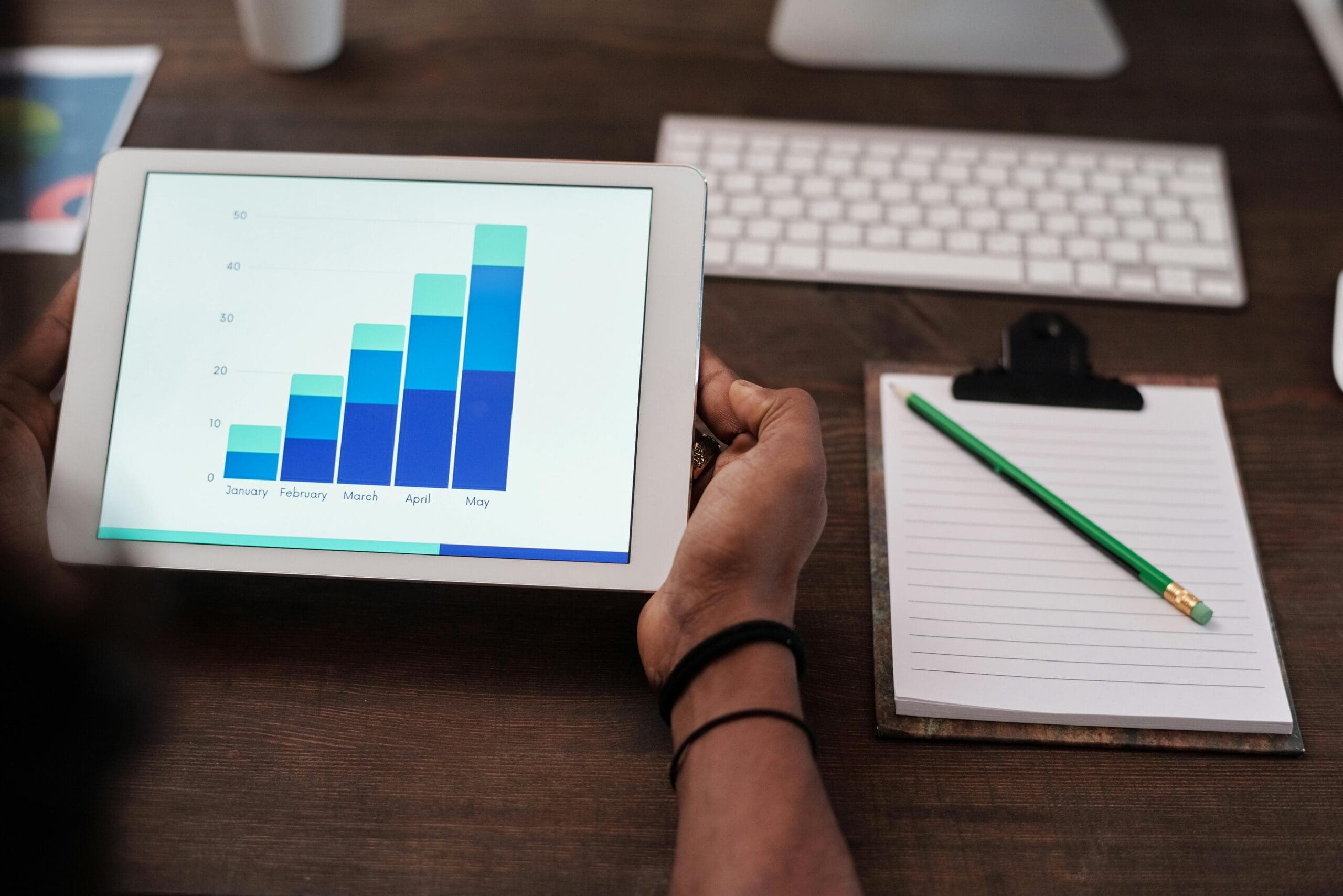 Person reviewing eCommerce analytics dashboard on tablet with growth chart for Shopify store performance.