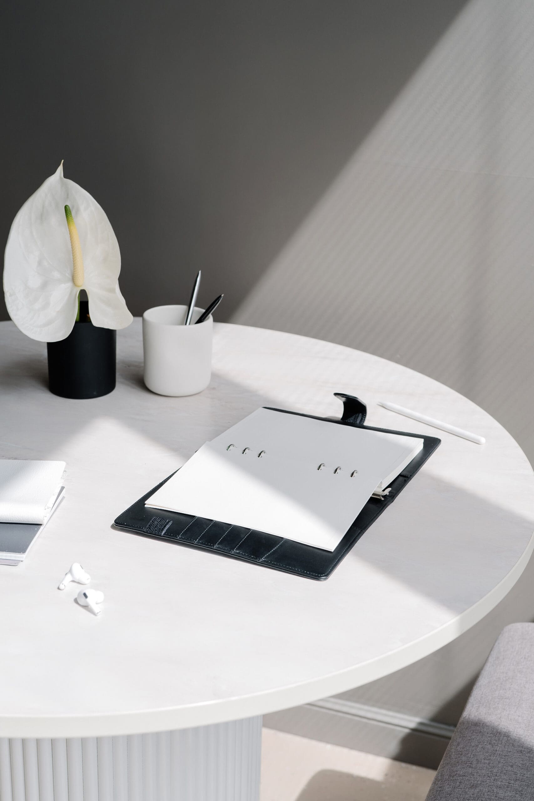Minimal workspace with a notebook, pen, and plant on a white desk, representing thoughtful Shopify web design and strategic store planning